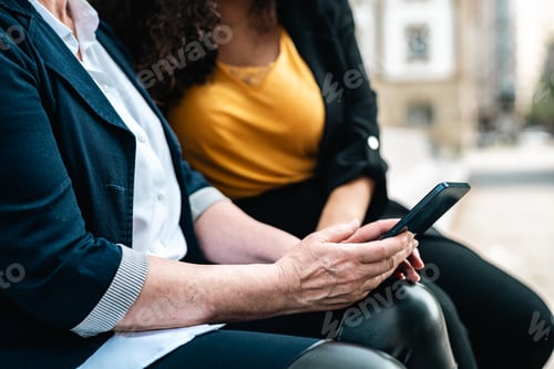 Preview: Two co workers chill during their free spare time in a park sharing ideas and stories. Showing phone