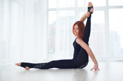 Preview: Beautiful young woman practices yoga asana Parivritta Kraunchasana at the yoga studio