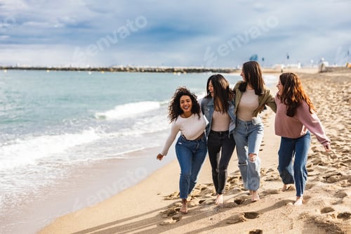 Preview: Friends of various ethnicities walk on the beach gossiping near the coast on their vacation