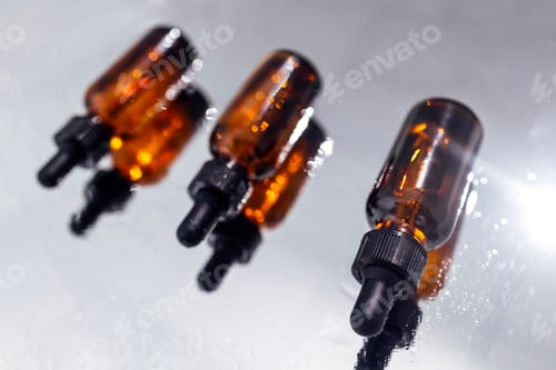 Preview: Group of bottles with drops on them and their reflection on a mirror surface