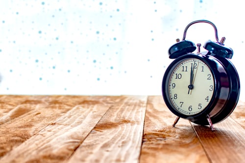 Preview: Black clock on an old wooden table.