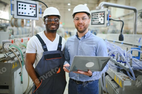 Preview: Two Diverse Professional Heavy Industry Engineers Wearing Safety Uniform and Hard Hats Working