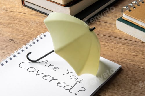 Preview: A small umbrella is placed on top of a notebook with the words "Are You Covered?"