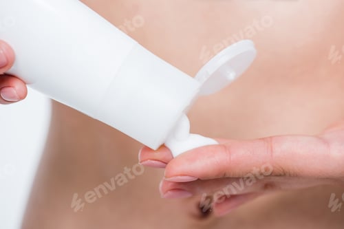 Vista previa: Close-up partial view of woman holding container with body lotion