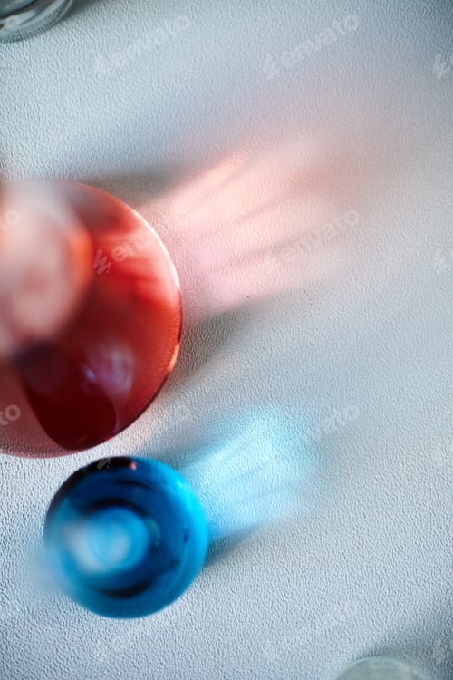 Preview: Top View of Light Reflection through Red and Blue Glass Beakers on Table