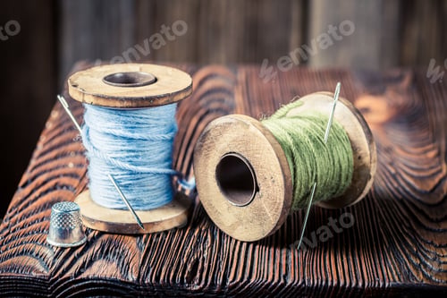 Preview: Closeup of vintage needle and threads on wooden table