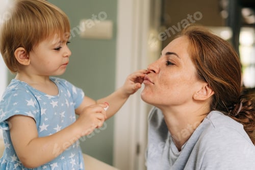 Preview: Child Applying Lipstick to an Adult in Home
