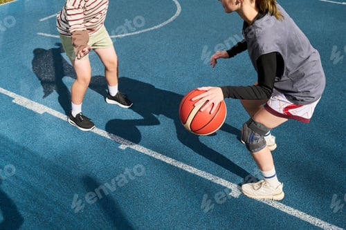 Preview: Teenage Girl Dribbling Basketball While Competing with Teenage Boy