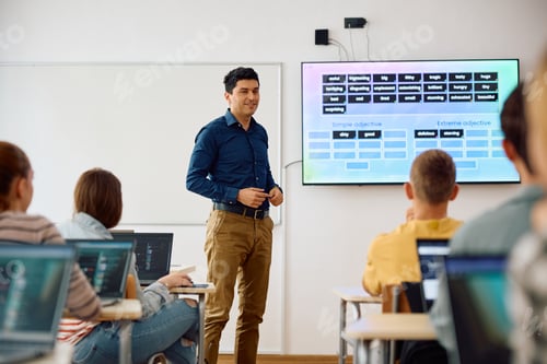 Preview: Happy computer science professor teaching students during a class in the classroom.