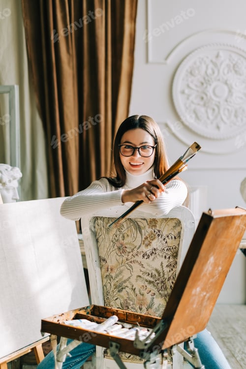 Preview: Smiling Woman Poses with Brushes in Art Studio