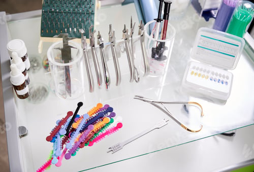 Preview: Glass table with dental instruments and orthodontic ligatures.