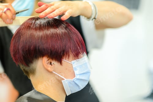Preview: Closeup shot of a female getting her hair done wearing a face mask - concept of the new normal