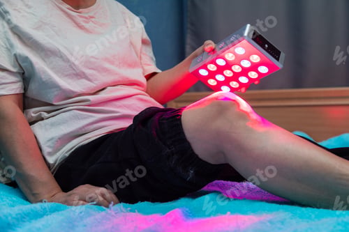 Preview: Closeup of treating sore leg with the red light therapy handheld device