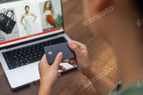 Preview: hands hold credit card against laptop screen online fashion clothing website, online shopping.