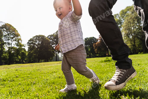 Preview: Father walking hand in hand with son in a park