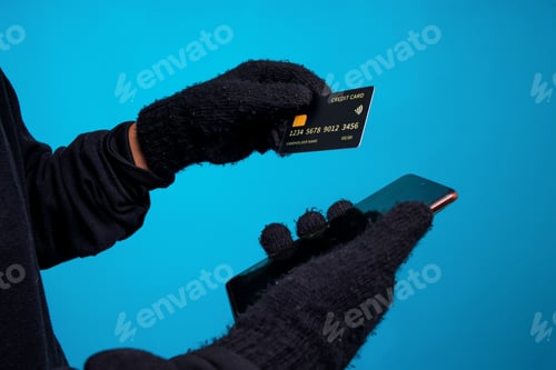 Preview: Close-Up of Hands In Gloves Holding Credit Card And Smartphone. Scammer Concept