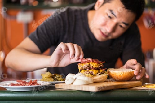Preview: Asian male cook preparing burger in cafe