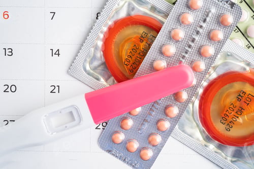 Preview: Pregnancy test and birth control pills on calendar, contraception health and medicine.