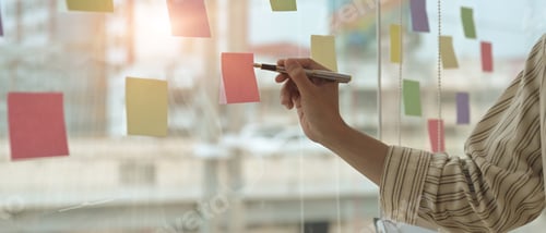 Preview: Cropped shot businessman manager writing strategy ideas on sticky notes in conference room.