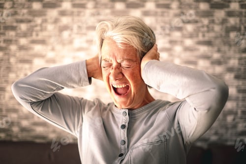 Preview: Desperate frustrated senior woman screaming in pain with hands on ears