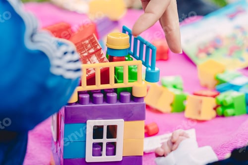 Preview: Closeup shot of a person playing with colorful building block toys