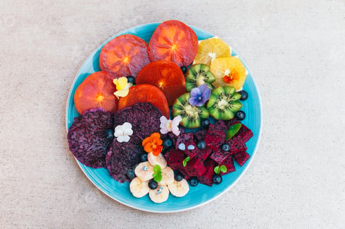 Preview: Tropical fruit assortment on plate against white background. Fresh slices of dragon fruit