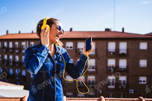Preview: Woman Enjoys Music on Phone with Headphones Outdoors