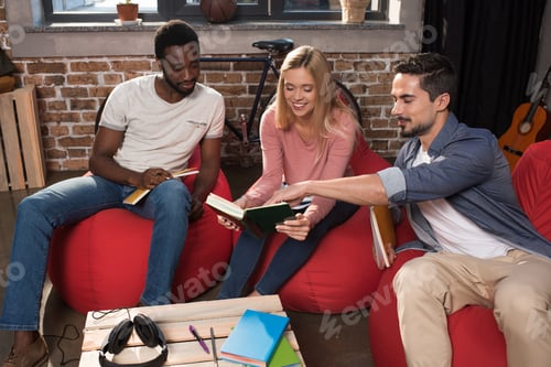 Preview: smiling multiethnic students with books studying together at home