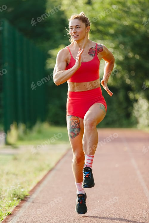 Preview: Muscular woman training sprint on outdoor running track