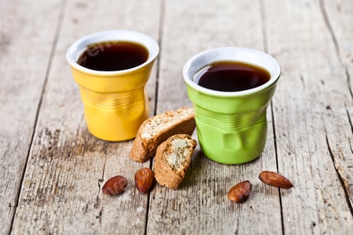 Preview: Two cups of coffee, fresh Italian cookies cantuccini and almond seeds on wooden table.