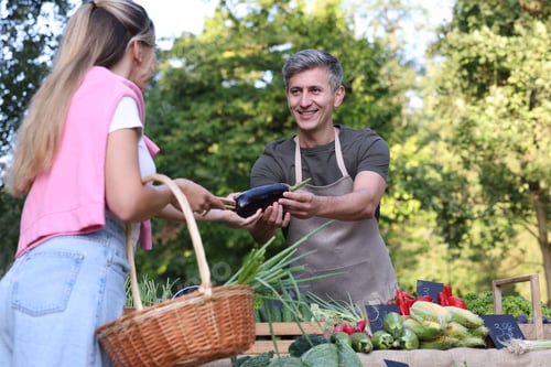 Preview: Woman choosing fresh vegetables from stall at farmer's market