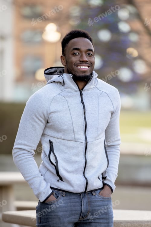 Preview: Portrait of a smiling African-American man in a park under sunlight with a blurry background
