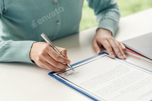 Preview: Close-up of a woman hand holding a pen about to sign contract documents at the office.