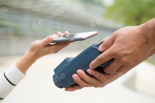 Preview: Woman pay by mobile phone with NFC technology at outdoor cafe