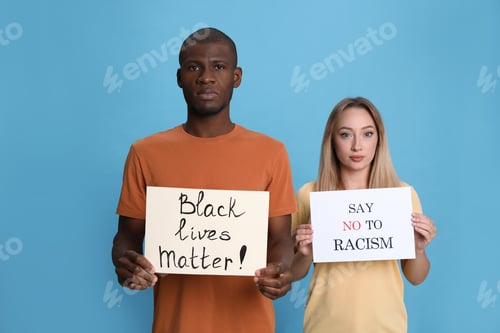 Preview: Young woman and African American man holding signs on light blue background. Racism concept
