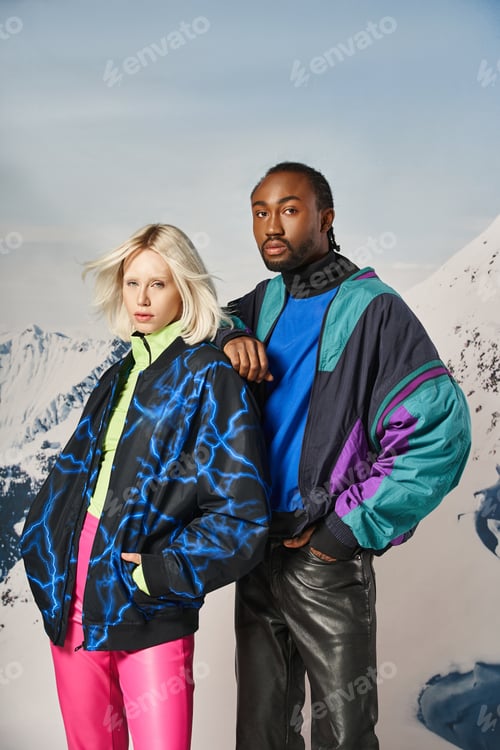 Preview: attractive young interracial couple in warm stylish attire looking at camera, winter concept