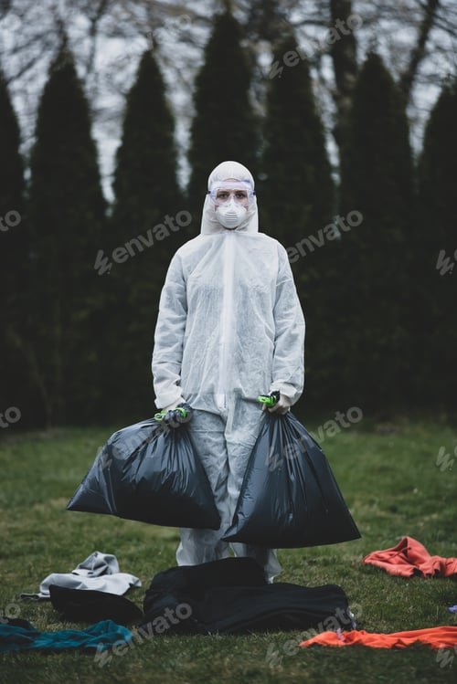 Preview: medic in a protective suit collects things left by infected people in bags