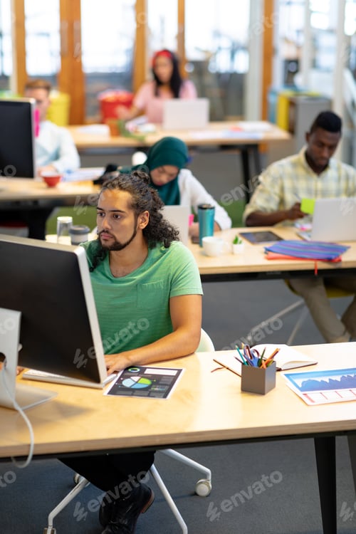 Preview: Front view of Mixed-race attentive businessman working on computer at desk in a modern office