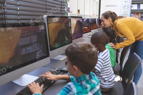 Preview: Happy Caucasian teacher teaching students while others students working on computers