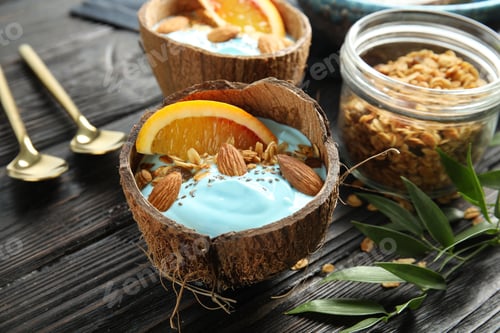 Preview: Composition with spirulina smoothie in coconut shell on wooden table