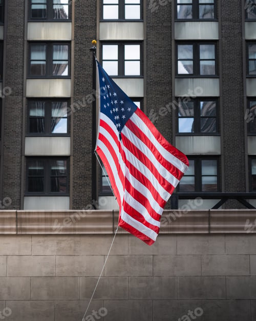 Preview: an american flag flying from the top of a building in front of large windows