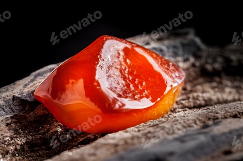 Preview: Natural amber. A piece of yellow and red semi transparent natural amber on piece of stoned wood