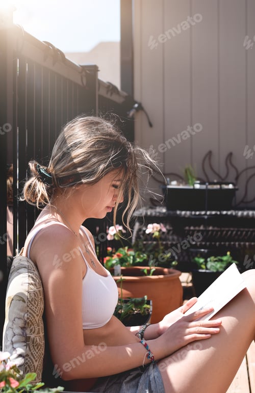 Preview: Young girl reading book outside on a balcony