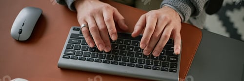 Preview: Header Image of Caucasian Man Typing on Wireless Keyboard While Working Remotely
