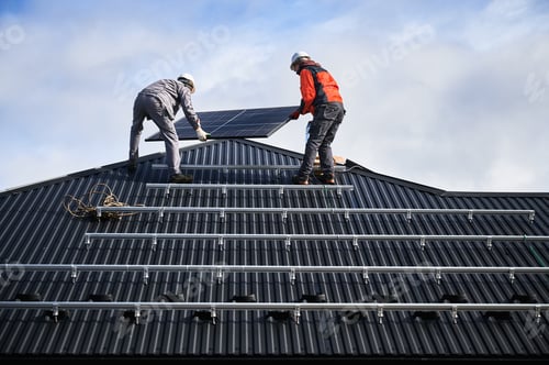 Preview: Technicians carrying photovoltaic solar module while installing solar panel system on roof of house