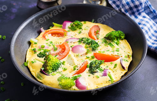 Preview: Omelette with broccoli, tomatoes and red onions in iron skillet. Italian frittata with vegetables.