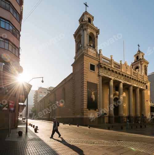 Preview: A solitary figure walking by a grand cathedral at sunrise