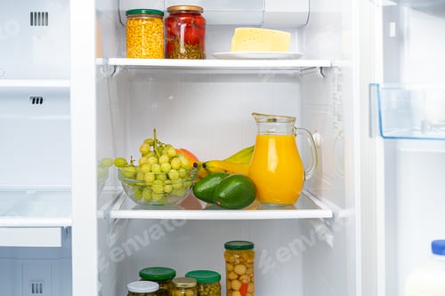 Preview: Glass pitcher of orange juice and fruits on fridge shelf