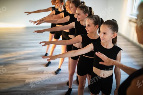 Preview: Group of fit happy children exercising ballet and dancing in studio together