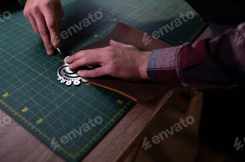 Preview: Production process. Young focused experienced master craftsman makes leather goods at his workplace